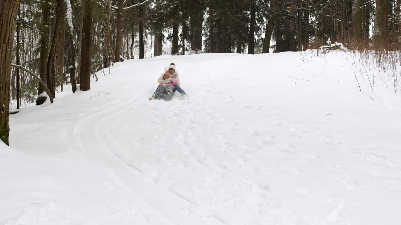 madre e hija en trineo en el bosque de invierno