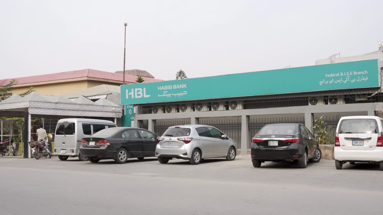 An impressive view captured on a bright day vividly illustrates traffic navigating a bustling street scene, with a striking view of the HBL bank building.