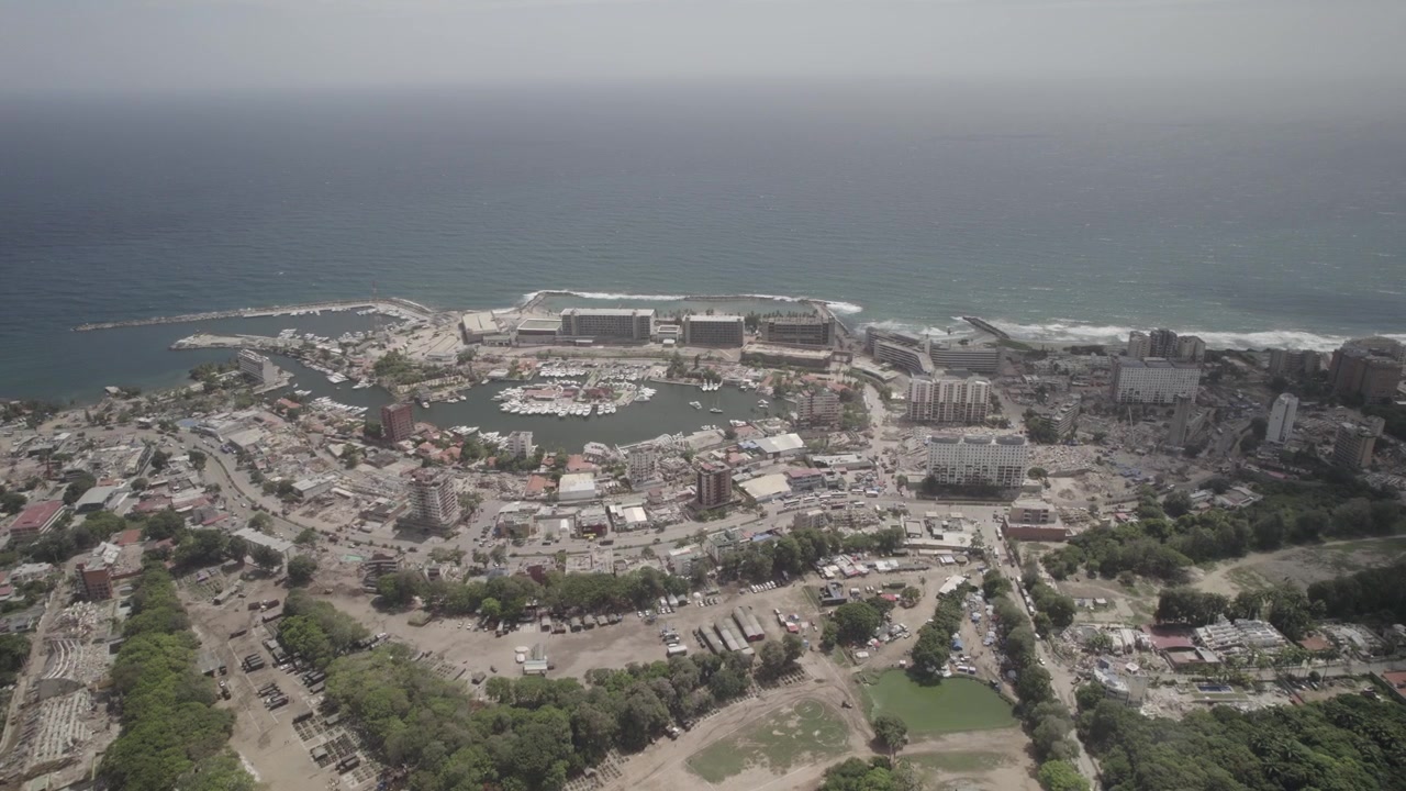 Panorama 4K D-Log da drone sul distretto costiero di La Guaira, Venezuela, colpito dal terremoto, che mostra aree urbane danneggiate e il porto turistico
