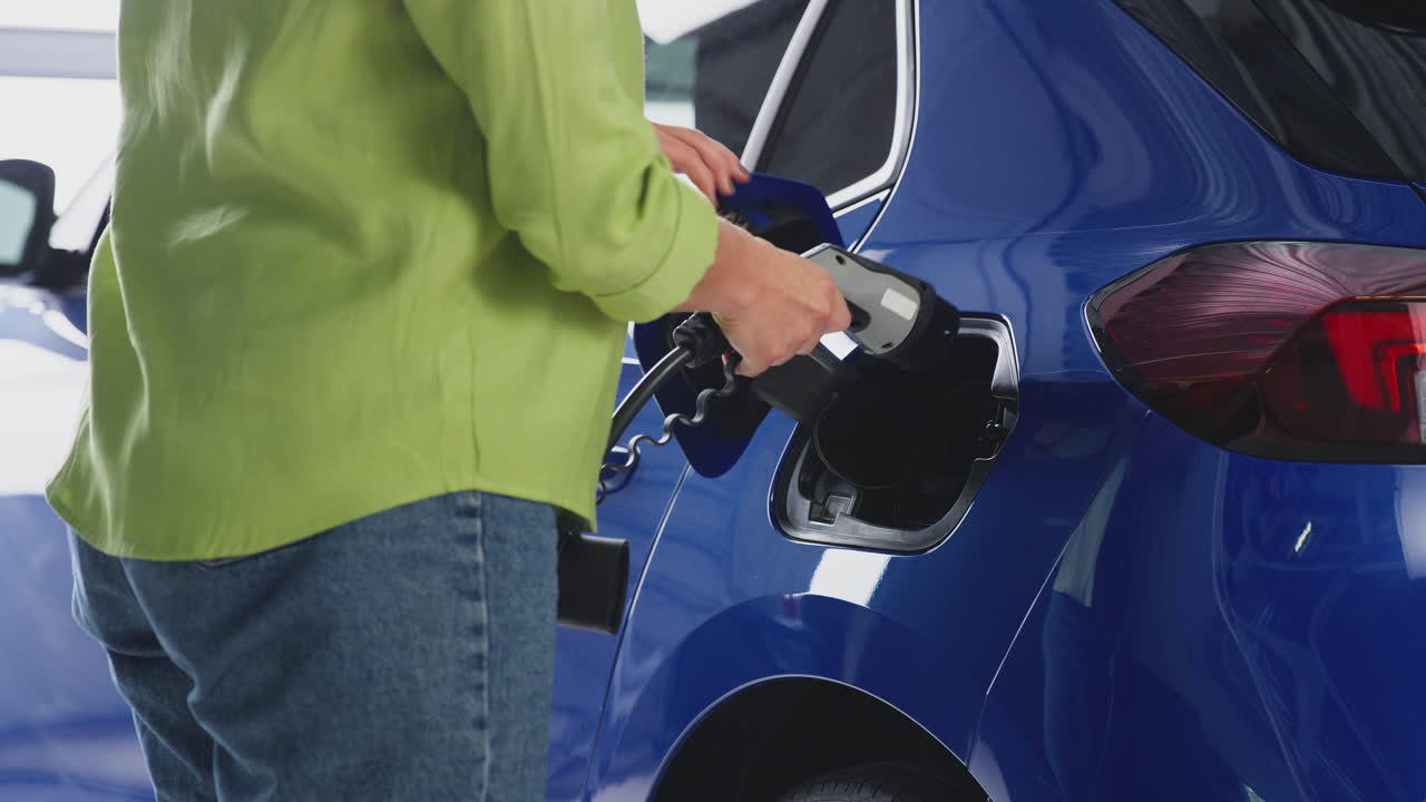 환경 친화적 인 제로 배출 전기 자동차에 충전 케이블을 연결하는 여성의 근접