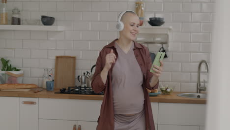 pregnant woman dancing and listening to music in the kitchen