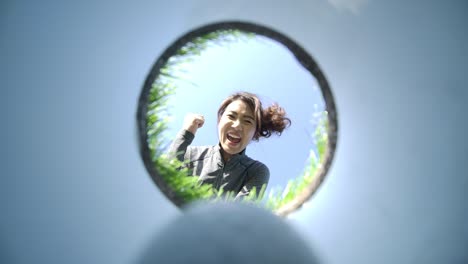 golf ball drops into a cup on green, smiling female golfer picking her ball out of a hole and celebrating. closeup view from the bottom of the hole looking up.