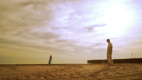 man throwing sand with foot. happy man having fun on beach. woman stand on beach