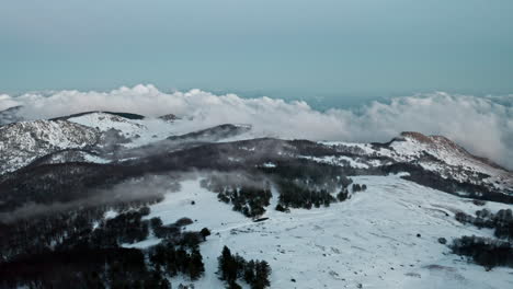 Paisaje-Montañoso-Nevado-Con-Nubes-Flotando-Sobre-Picos-Y-Bosques