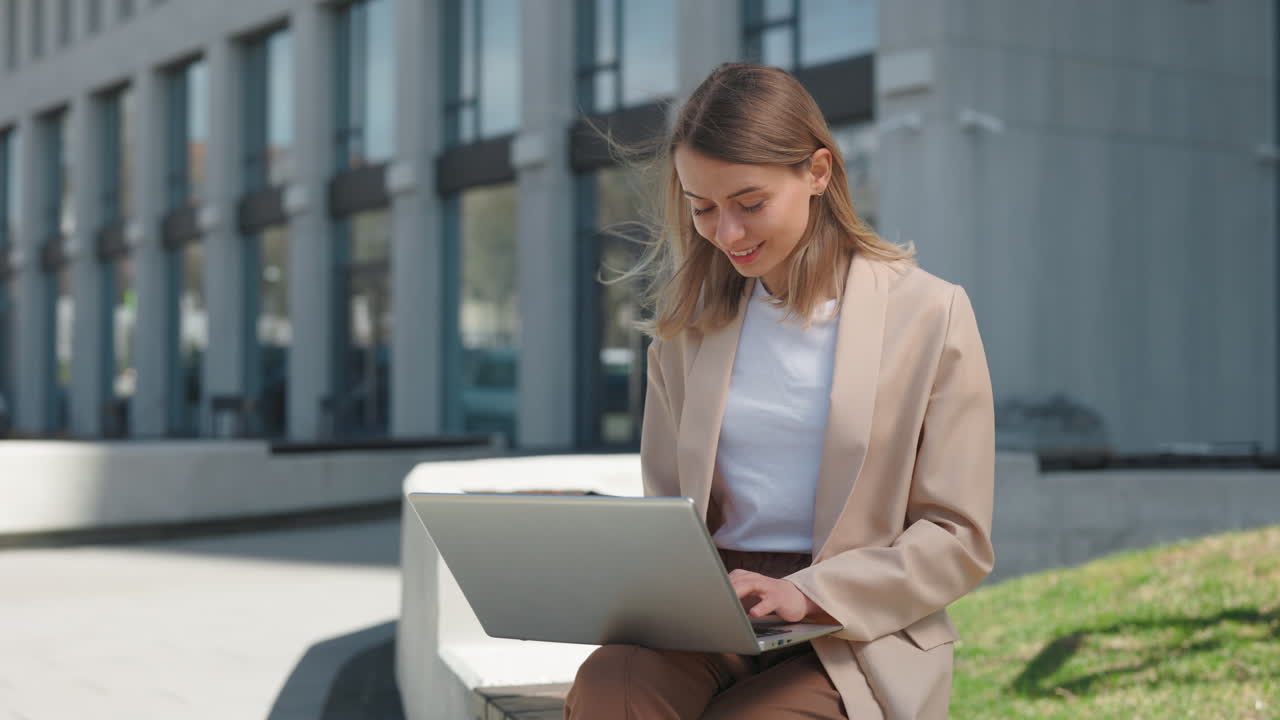 Giovane donna sorridente che lavora al laptop in un ambiente urbano