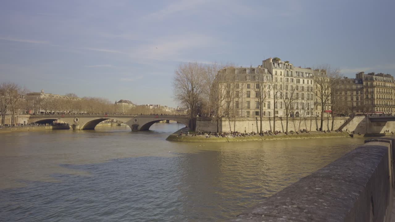Seine River in Paris, historic stone bridge, people enjoying sunny winter day long shore, copy space