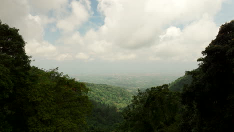 Drone-flying-over-lush-mountains-forest-with-valley-in-background-on-foggy-day,-Bali-in-Indonesia