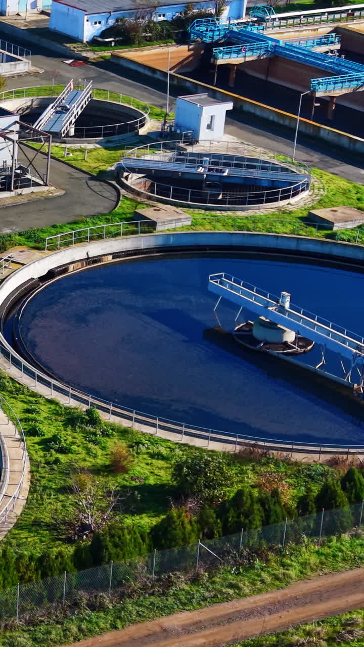 High angle view of a large circular sedimentation tank with a rotating bridge in a treatment facility. Secondary clarifier tank in water plant. Vertical video