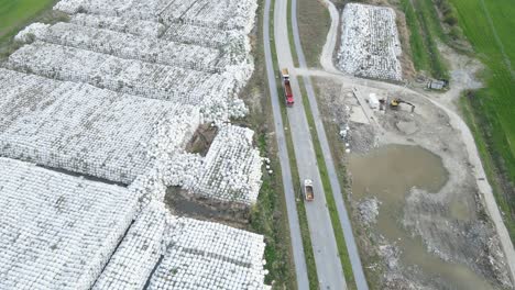 drone approaching landfill dump junkyard with cube of plastic inorganic pollution toxic waste garbage