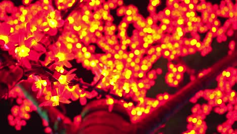 bright red christmas lights hanging on branches of tree and glowing at night