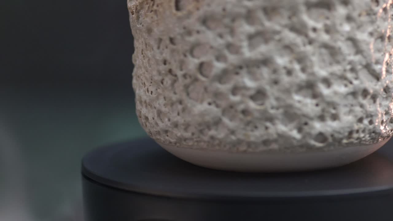 옥수수 질감으로 된 세라 유리 바닥의 크로스업 매크로가 축을 중심으로 휘어져 있습니다.