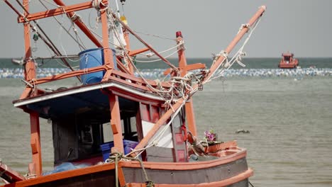 un primer plano de un tradicional barco de pesca de calamar tailandés amarrado y varado durante la marea baja en tailandia