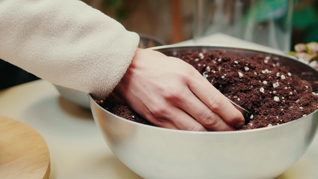 Close-Up of Hand Scooping Potting Soil from a Bowl