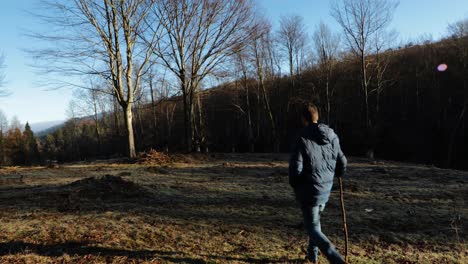 Man-walking-with-a-stick-through-the-forest