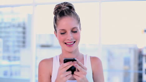 Cute-young-woman-text-messaging-with-her-smartphone