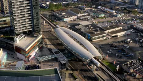 aerial backward drone shot of brentwood town centre skytrain station and its surroundings