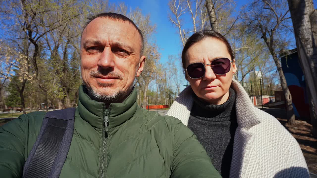 Ett par tar en selfie tillsammans i en park en solig dag