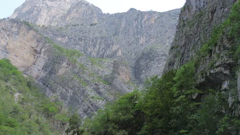 Ein-Roter-Lastwagen-Mitten-In-Den-Bergen-überquert-Straßen-Zwischen-Riesigen-Felsen-Und-Vermeidet-Erdrutsche-Auf-Einer-Schwer-Befahrbaren-Straße,-Die-Man-In-Der-Ferne-Sehen-Kann