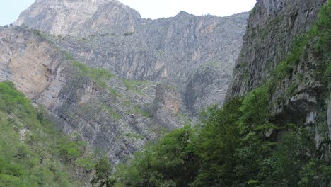 camión rojo en el medio de las montañas cruzando calles que están entre las enormes rocas y evitando deslizamientos de tierra en una carretera que es difícil de navegar y en la distancia se puede ver