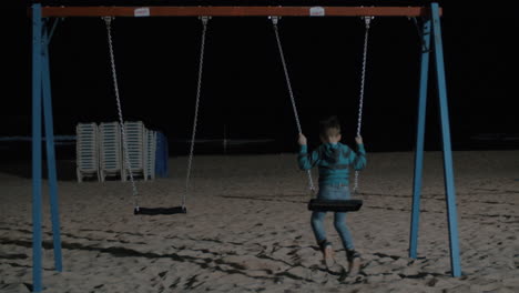 kid swinging alone on the beach at night