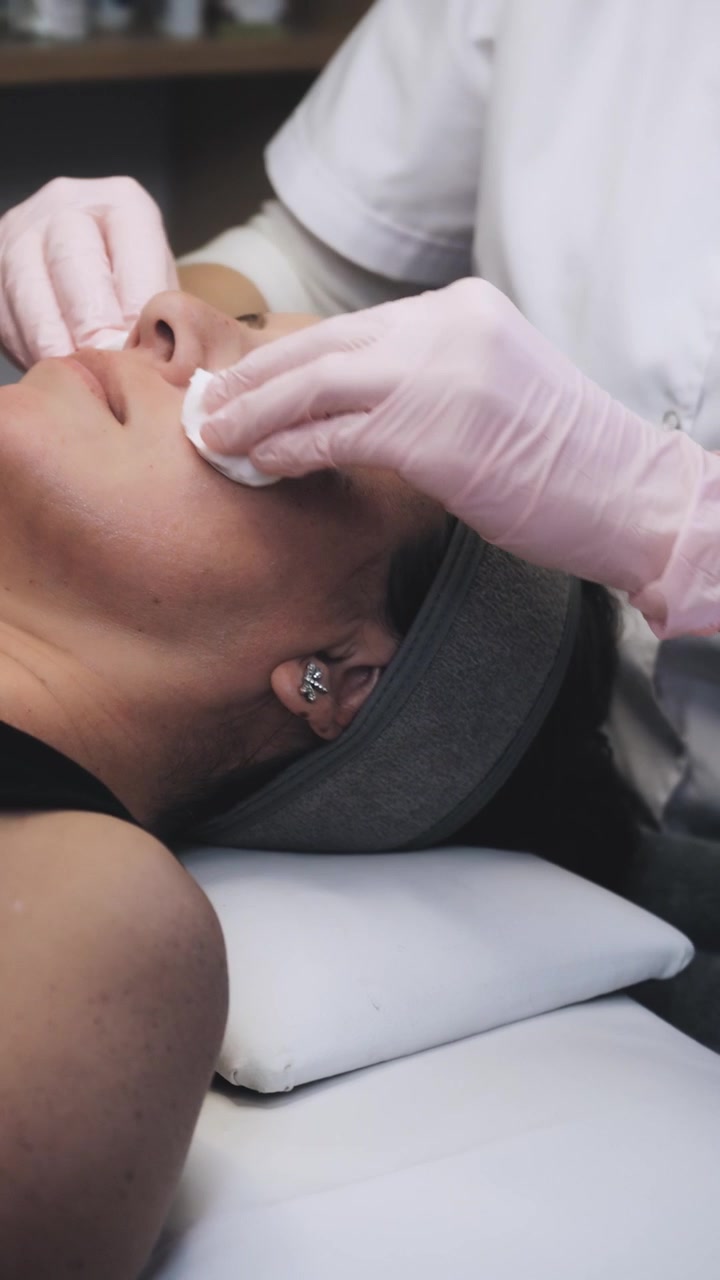 Esteticista limpiando el rostro del cliente antes del tratamiento HIFU