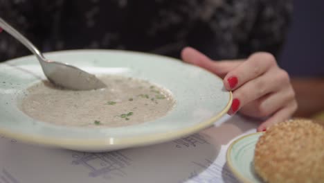 cooling soup with spoon close up.person hand with spoon mixing hot soup.