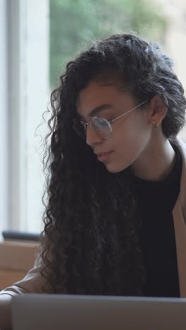 young woman working on a laptop and drinking coffee at a cafe