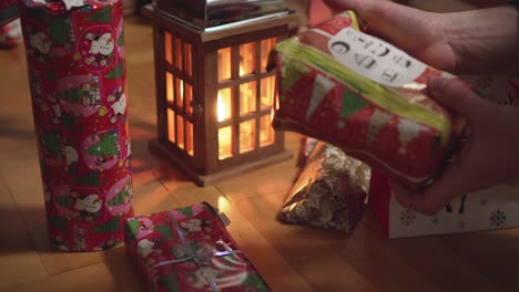 choosing christmas gift under tree, male hands, picking up and taking back, closeup