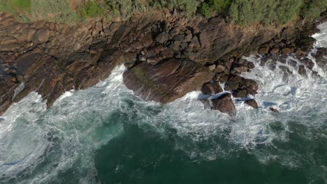 60 fps slow motion establishing aerial drone shot of waves crashing against rocks in tropical southern sri lanka