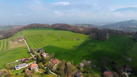 Drone-shot-of-village-in-the-middle-of-green-meadows-in-the-foothills-of-the-Chartreuse-Massif,-Isère,-Velanne-in-Auvergne-Rhône-Alpes---France