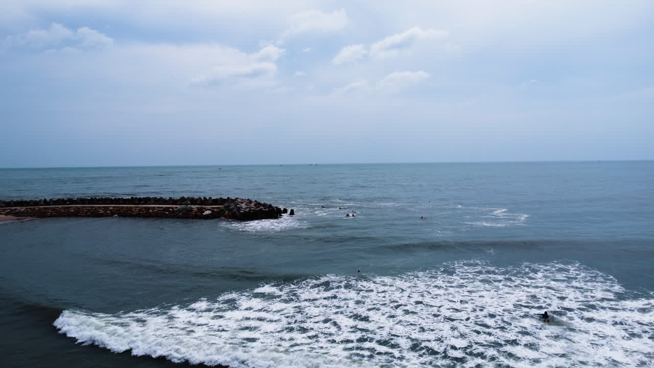 방파제 파도 차단기에 의해 보호되는 해안으로 굴러가는 부드러운 흰색 거품 파도