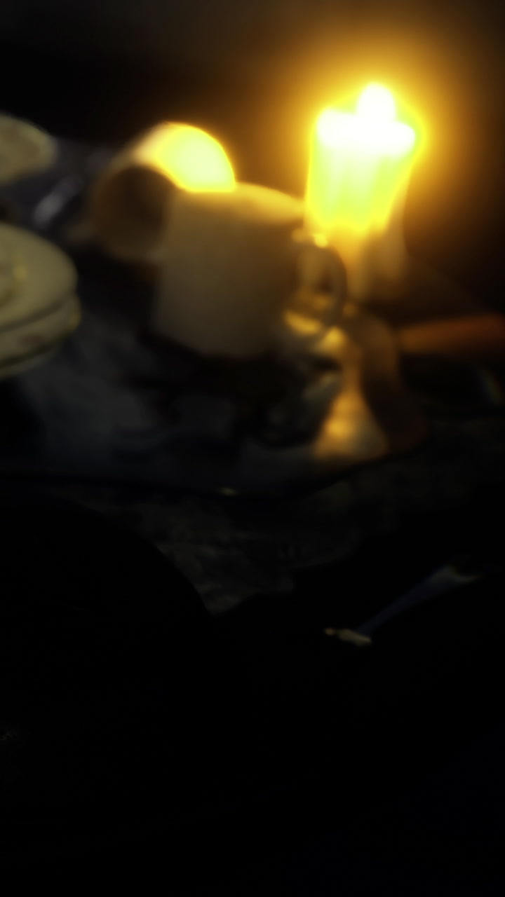 Warm candlelight by a table with a mug and a plate in a dim room setting