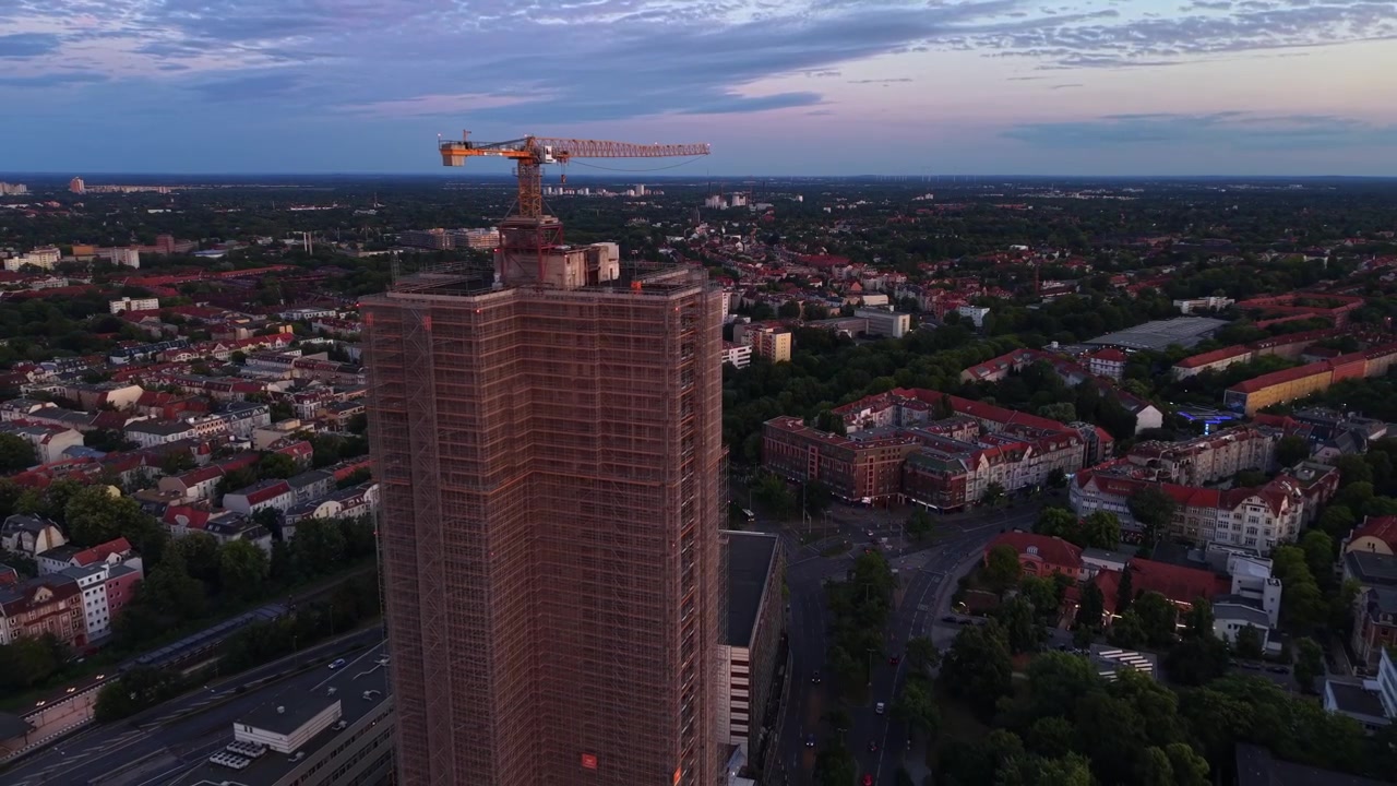 Berlim, mostrando um edifício alto em construção e um guindaste alto, contra um céu de fim de tarde. Ótima vista aérea, panorama de drone com voo reverso.