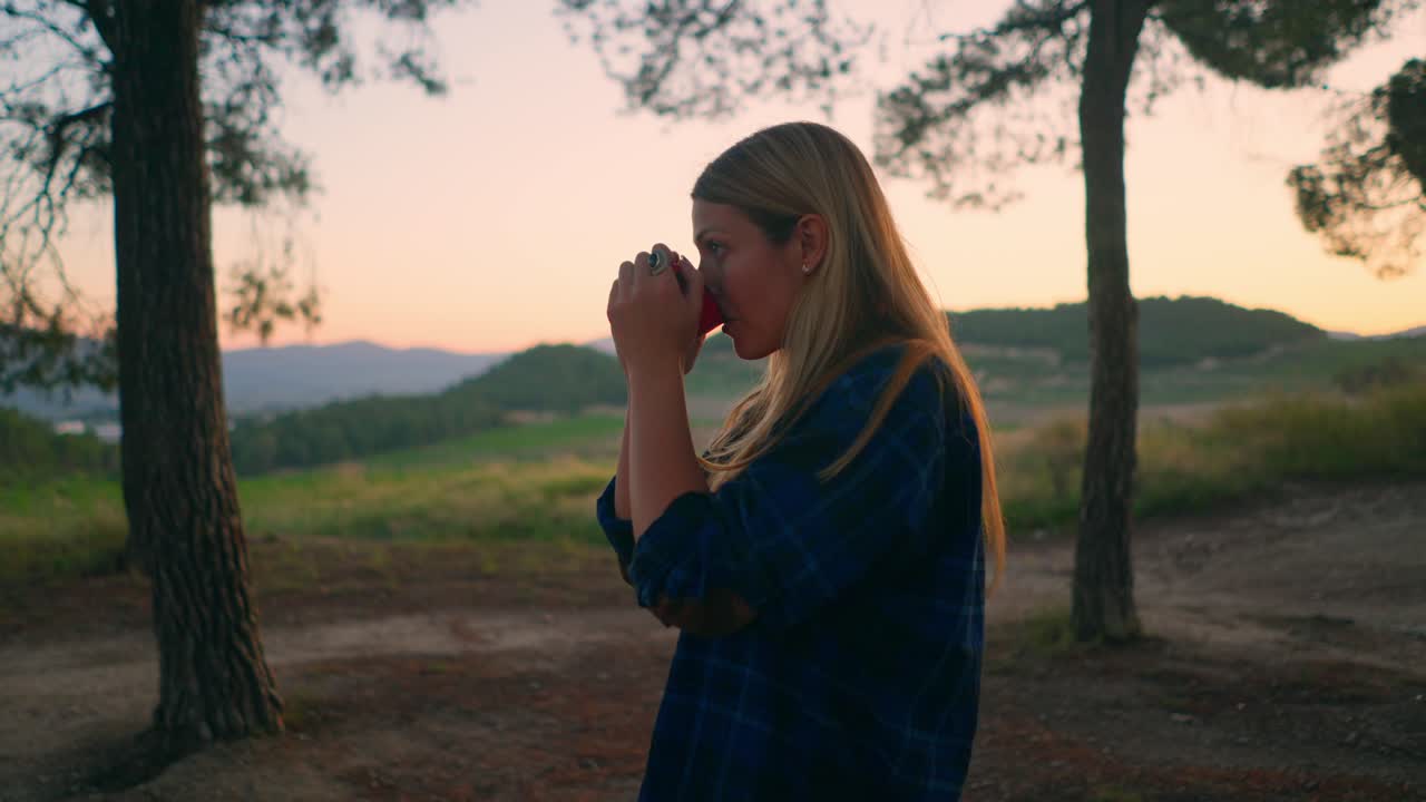 젊은 여성은 캠핑을 갔다가 숲에서 커피를 마시며 일어난다