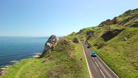 aerial video of the causeway coastal route in county antrim, northern ireland, uk, on a bright and sunny day. cars travel along the cliff-side road. filmed in 4k, 60fps and with rec709 color.