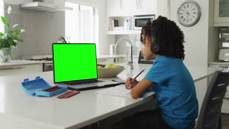 Animation-of-biracial-boy-in-headphones-having-online-lessons-on-laptop-with-copy-space-home