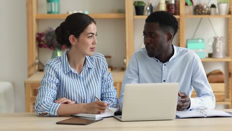 colegas multirraciales se sientan en el escritorio con la computadora portátil discutir software corporativo