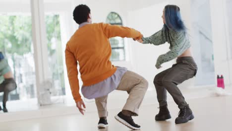 bailarines masculinos y femeninos felices y diversos bailando frente al espejo en un estudio de baile, cámara lenta