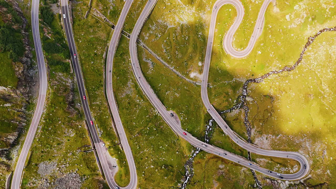 Stig nedover den svingete veien i den grønne fjellskråningen. Droneflyging over den velkjente Transfagarash-motorveien i Karpatene, Romania