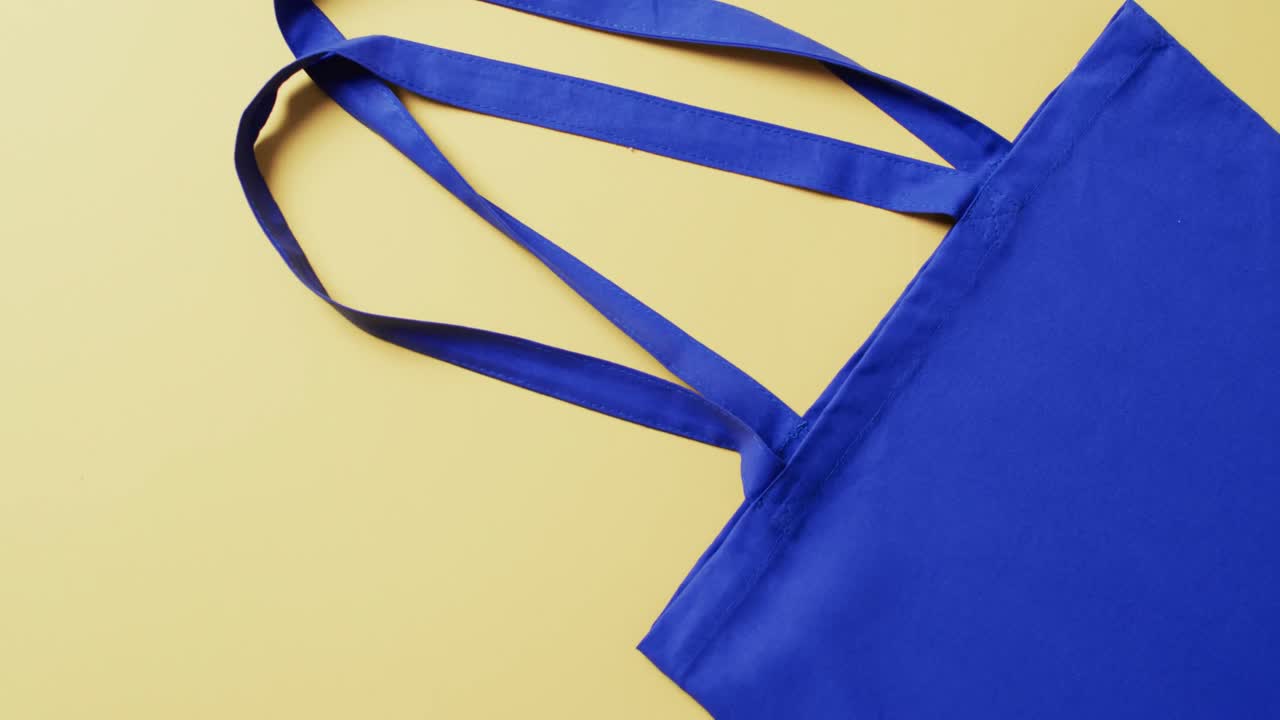 video de una bolsa de lienzo azul con espacio de copia en fondo amarillo