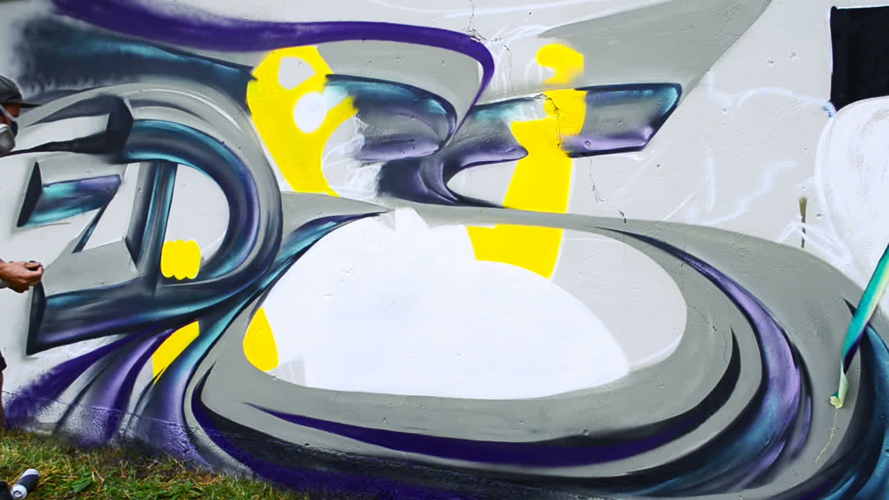 Konstnären ritar graffiti på ett staket. Graffiti på ett staket