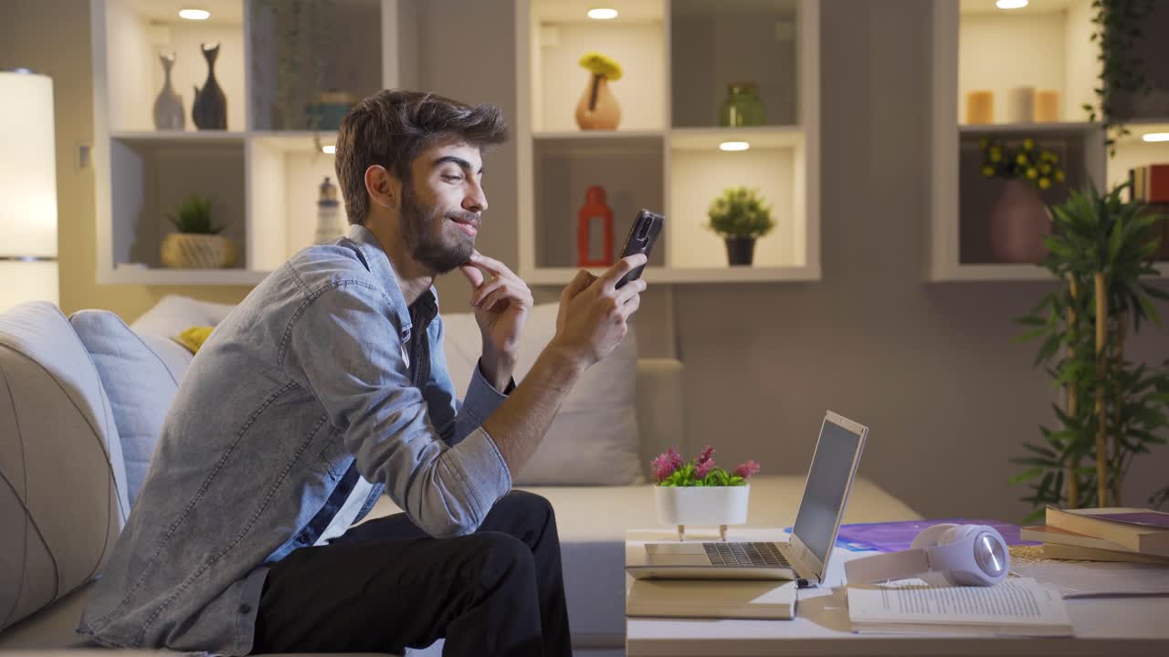 Man using social media on phone laughing at night at home.