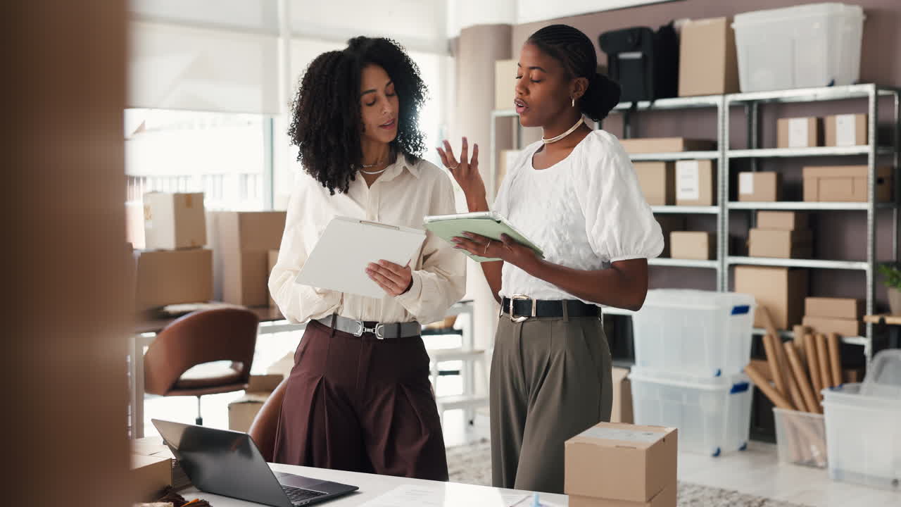 Two Businesswomen Discussing Logistics and Inventory in Small Office