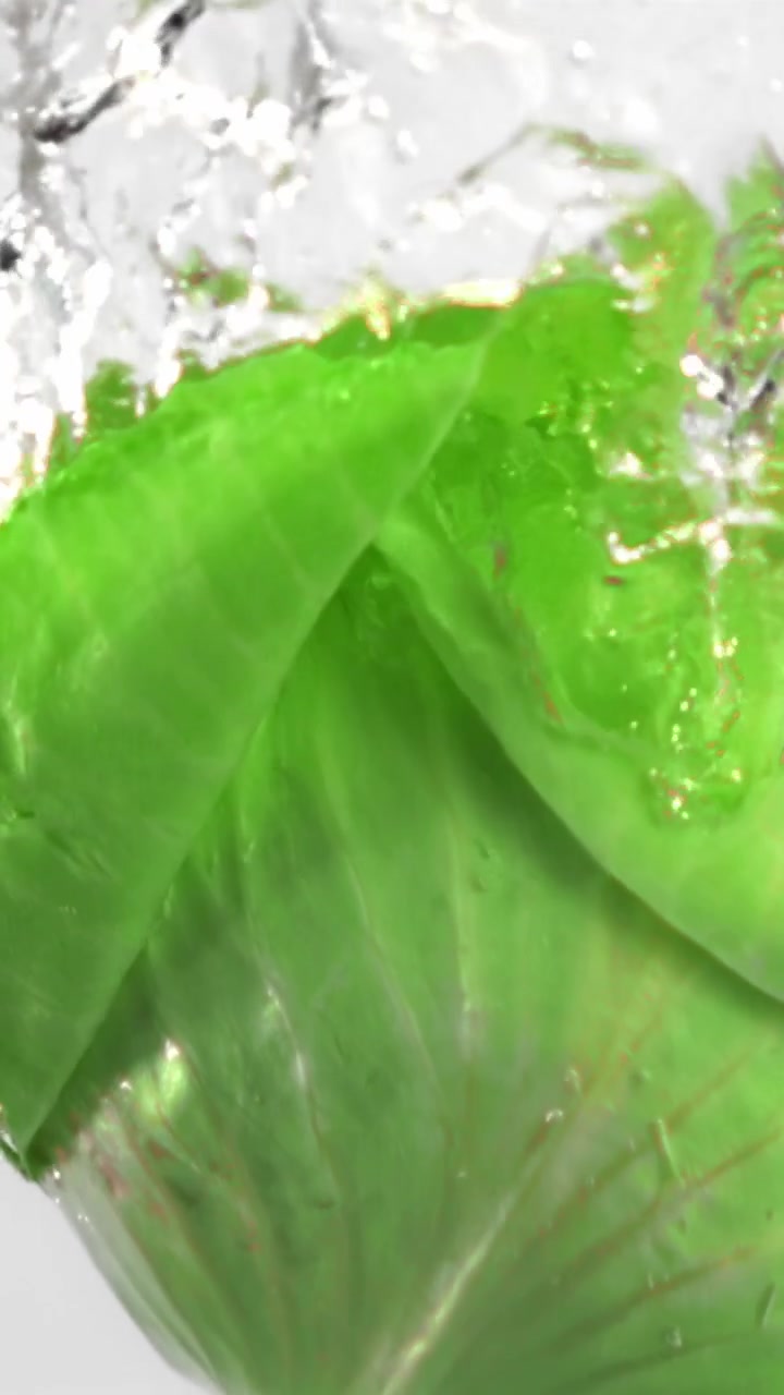 Foglia di lattuga verde fresca che schizza in acqua limpida