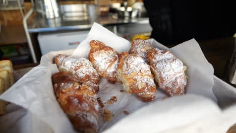 fresh croissants with powdered sugar on bakery paper