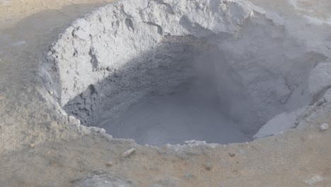 active geothermal mud pot in icelandic terrain