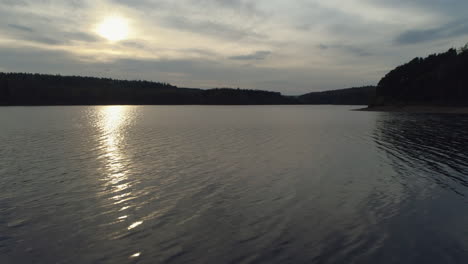 low aerial drone shot into the sun over swinsty reservoir at golden hour in yorkshire uk