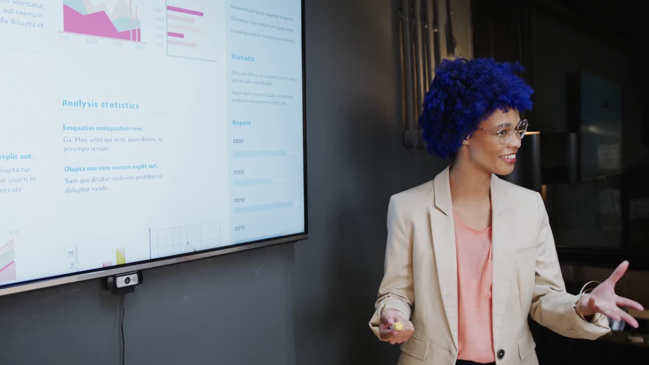 Biracial casual businesswoman with blue afro making presentation in office, slow motion