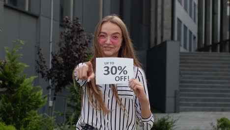 smiling girl showing up to 30 percent off inscriptions signs, rejoicing good discounts, low prices