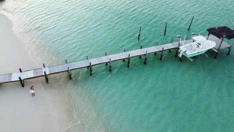 a woman walks towards a boardwalk on the white beach in the bahamas